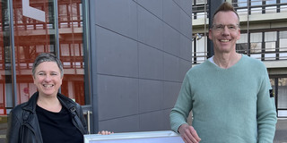 Eva Cendon (links) und Uwe Wilkesmann (rechts) stehen neben dem Plakat zur GfH.